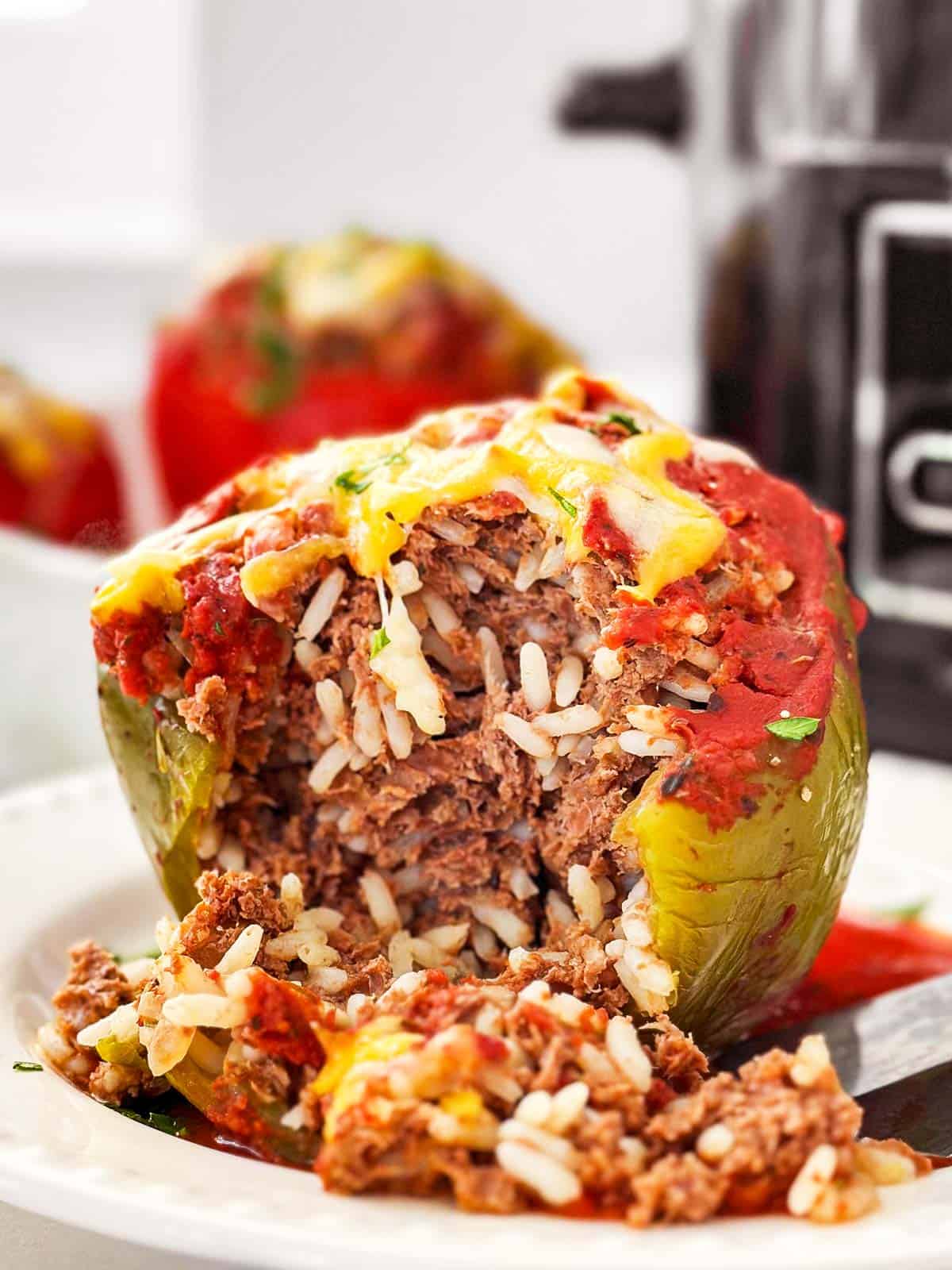 frontal view of stuffed pepper on white plate with some bites taken out