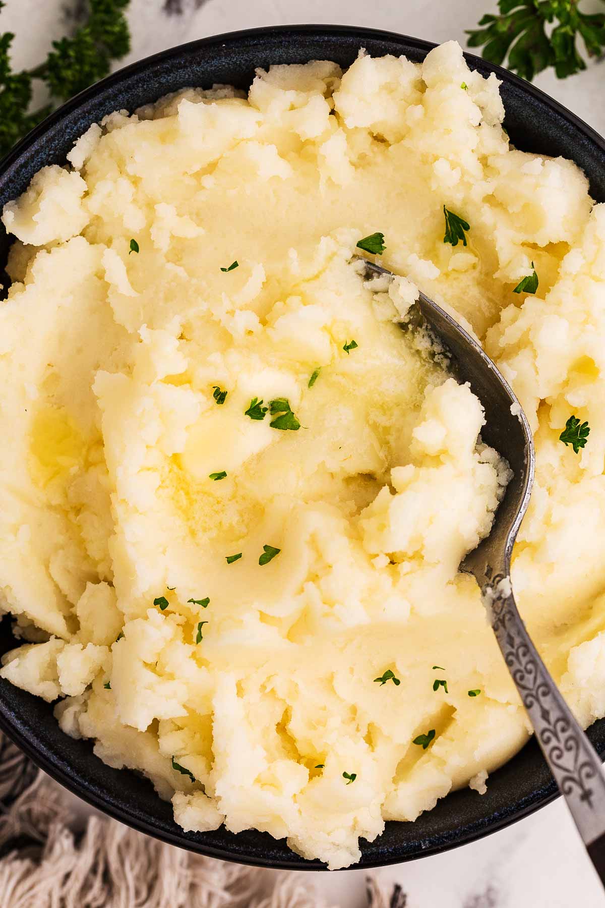 overhead view of mashed potatoes in black bowl with a spoon stuck in