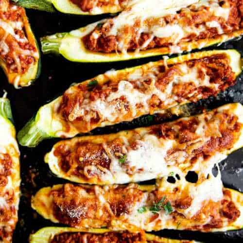 overhead closeup view of stuffed zucchini boats on black baking sheet